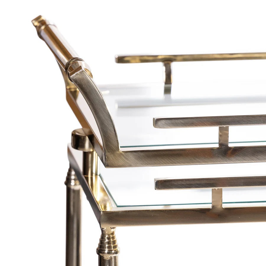The SPIGA GOLD BAR CART by ZODAX features a vintage Italian-inspired design with elegant gold framing, mirrored glass shelves on both tiers, and smooth-rolling four-wheel mobility. Displayed against a white background, this piece is both stylish and functional.