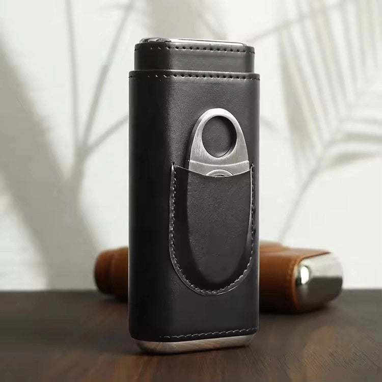 The AMERICAN LEATHER GOODS Leather Cigar Case with Wood-Lined Humidor and Cutter in Black rests on a wooden surface, with another travel humidor case in brown visible in the background.