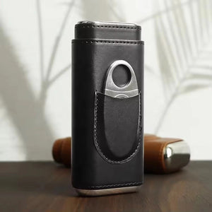 The AMERICAN LEATHER GOODS Leather Cigar Case with Wood-Lined Humidor and Cutter in Black rests on a wooden surface, with another travel humidor case in brown visible in the background.