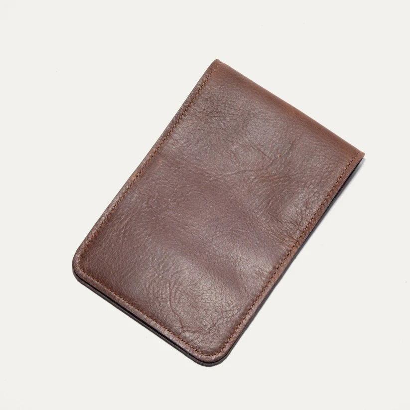 The WILL LEATHER GOODS GOLF YARDAGE BOOK IN COGNAC, by WILL LEATHER GOODS, features full-grain brown leather and a minimalist design—ideal for holding cards or a golf scorecard. It is shown closed on a plain white background.