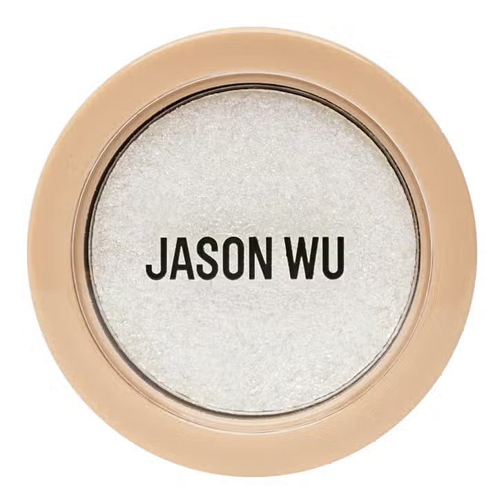 A circular makeup compact named &quot;READY TO SHIMMER HEAVENLY 2&quot; by JASON WU BEAUTY features a beige outer rim and a transparent lid, revealing a shimmery white powder inside. The bold black text &quot;JASON WU&quot; is printed on the lid, making it ideal for applying with an eye shadow brush to enhance the shimmer effect on your eyelids.