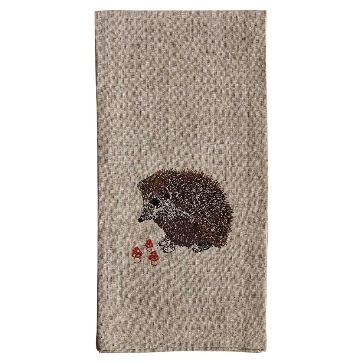 A HEDGEHOG WITH MUSHROOMS LINEN TEA TOWEL by CORAL & TUSK hangs from the handle of a white stove in a kitchen.