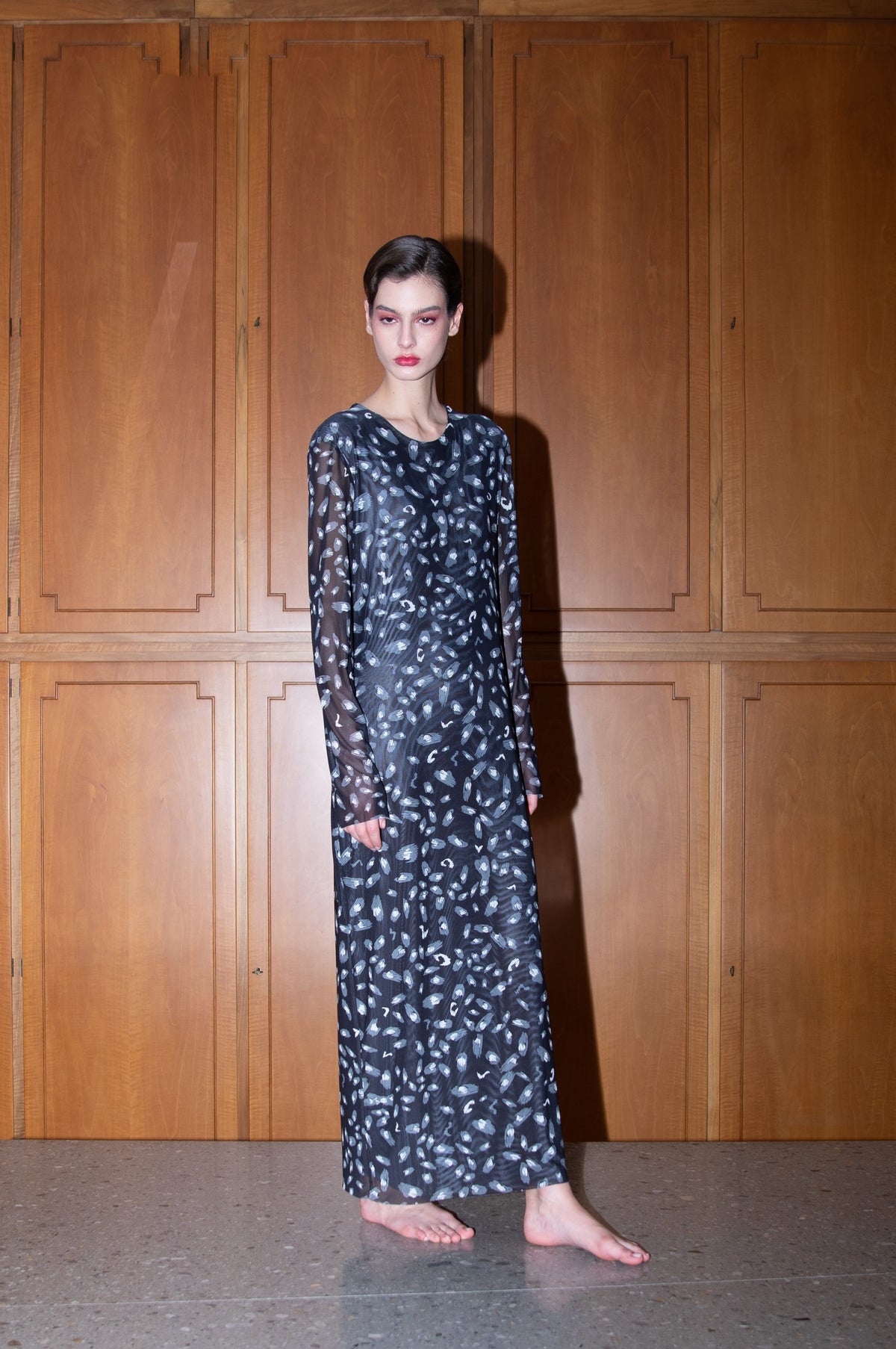 The FRANCO FERRARI BALLET MESH MAXI DRESS is a long-sleeved, ankle-length black stretch mesh dress with a sheer overlay featuring scattered gray and white abstract patterns, shown against a white background.