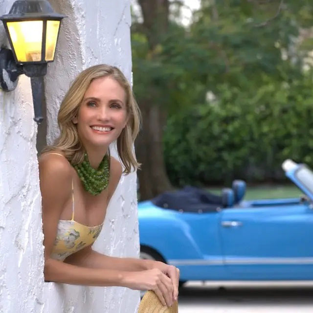 The FAIRCHILD BALDWIN - THE BELLA NECKLACE showcases layered strands of iridescent green Italian resin beads with a faceted design for a shimmering effect, finished with a smooth light green clasp that complements its vibrant hues.