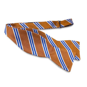 The BIRD DOG BAY - ON AIR STRIPE SILK BOW TIE IN ORANGE AND BLUE, a luxurious silk self-tie bow tie handmade in the USA, features vibrant orange with diagonal blue and white stripes and is neatly tied against a plain white background.