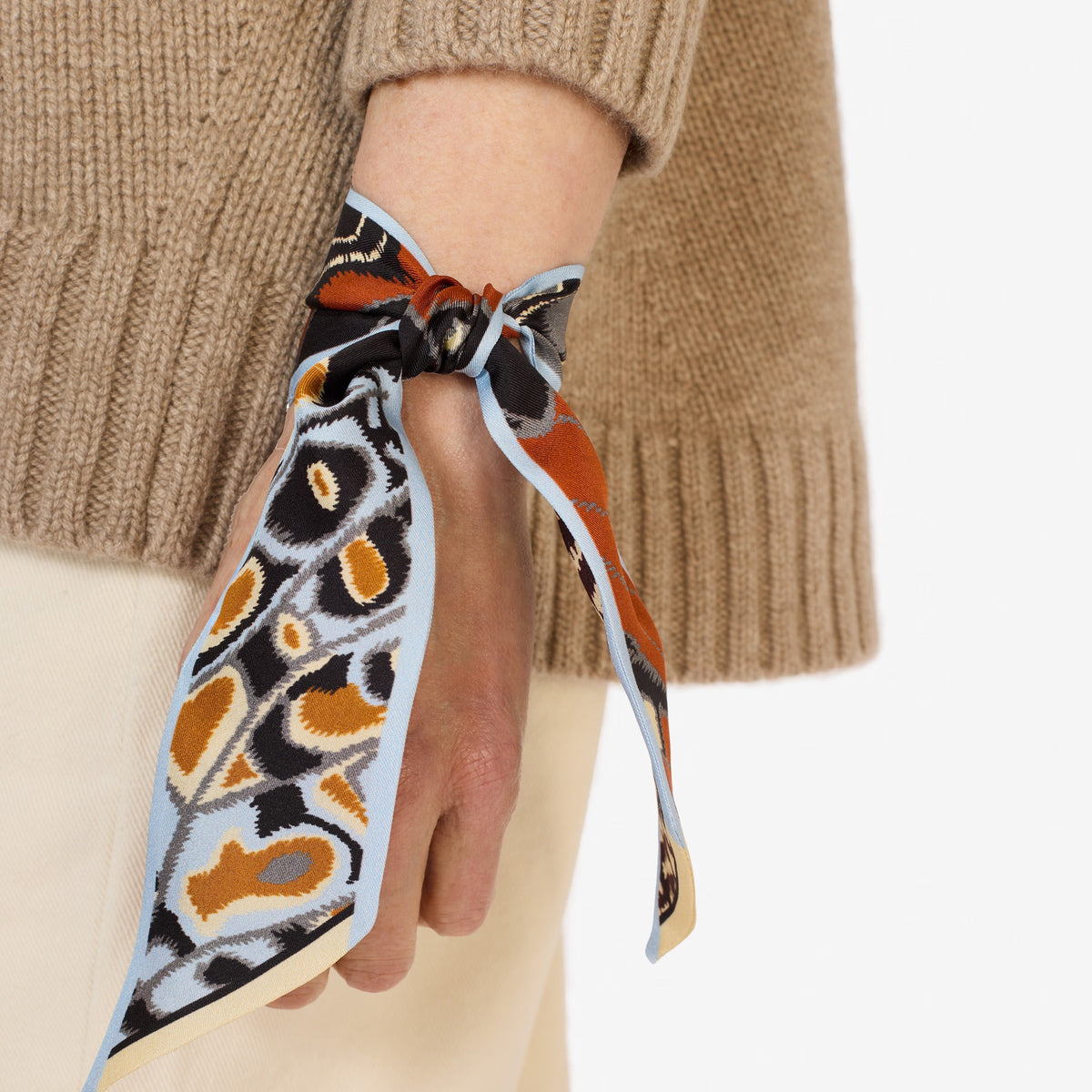The INOUI EDITIONS - PAPILLON (BUTTERFLIES) SILK RIBBON by INOUI features a butterfly wing print in orange, black, white, and yellow—an elegant silk scarf to elevate any outfit. Displayed on a white background.