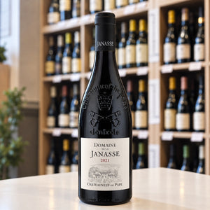 A bottle of JANASSE ‘TRADITION’ CHATEAUNEUF-DU-PAPE 2021 from WINE: FREEDOM BEVERAGE, featuring an embossed crest on the neck and a detailed illustration of a vineyard on the label.