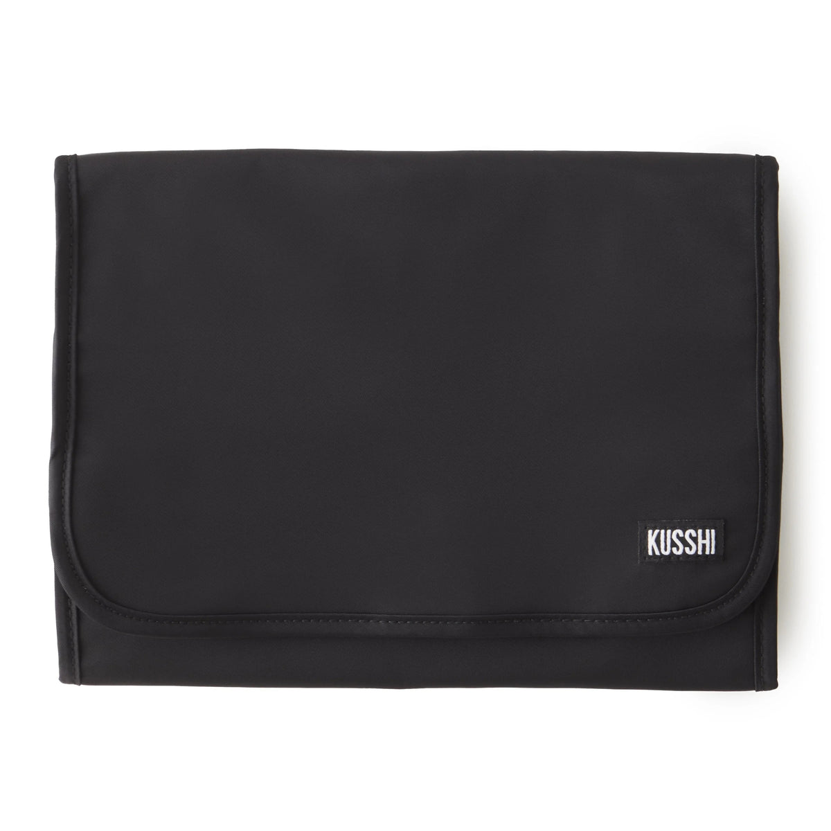 The KUSSHI - LARGE TRAVEL JEWELRY ORGANIZER by KUSSHI is a rolled-out jewelry organizer made with a premium nylon exterior. It features multiple transparent zippered compartments, offering compact travel storage for rings, earrings, bracelets, necklaces, and a watch. The organizer comes in pink with black edges and includes a black hanging loop at the top.