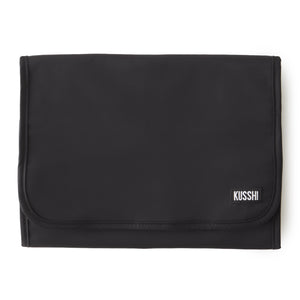 The KUSSHI - LARGE TRAVEL JEWELRY ORGANIZER by KUSSHI is a rolled-out jewelry organizer made with a premium nylon exterior. It features multiple transparent zippered compartments, offering compact travel storage for rings, earrings, bracelets, necklaces, and a watch. The organizer comes in pink with black edges and includes a black hanging loop at the top.