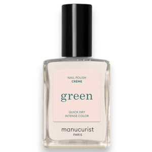 A hand with neatly manicured off-white nails, painted with MANUCURIST - GREEN™ NAIL POLISH IN CREAM by MANUCURIST INC, rests on a rich red textured fabric, creating a striking contrast between the nail color and the background.