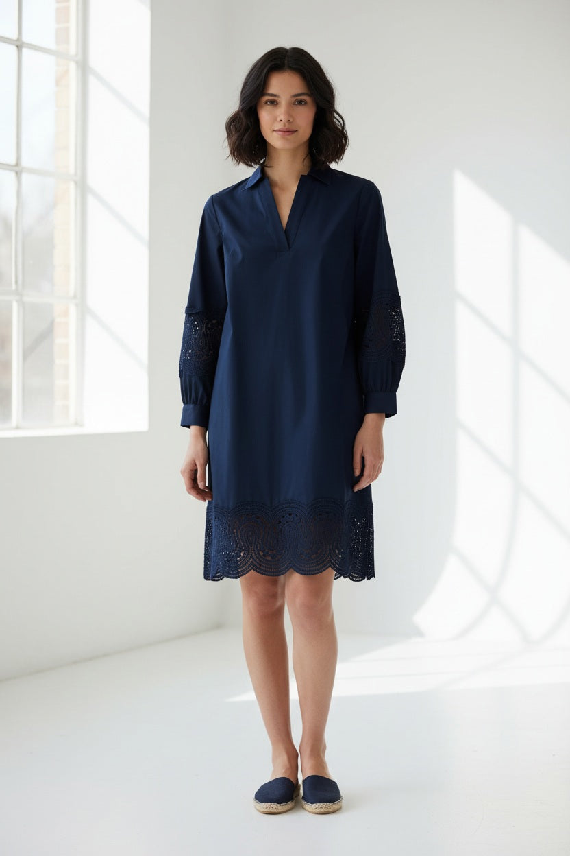 A woman with long red hair wears the HINSON WU Mona Bracelet Sleeve Lace Stretch Polished Cotton Dress in Navy. Crafted from stretch polished cotton, the dress features eyelet lace details on the sleeves and hem. She stands against a plain light background, looking slightly to the side with a neutral expression, her outfit highlighting its polished finish.