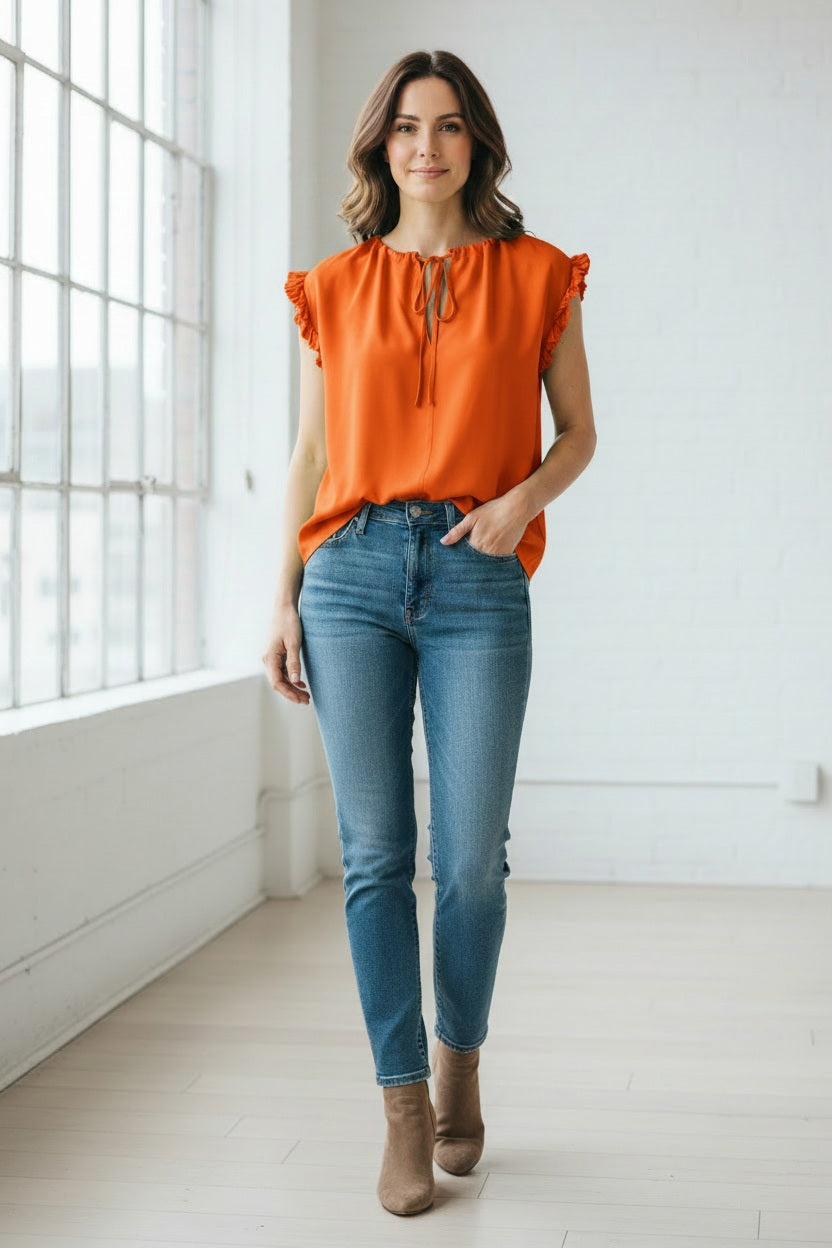 A woman wears the MEIMEIJ Cap Sleeve Blouse, a light green viscose top with ruffle cap sleeves and a tied neckline from MEIMEIJ, paired with white bottoms against a plain light background.