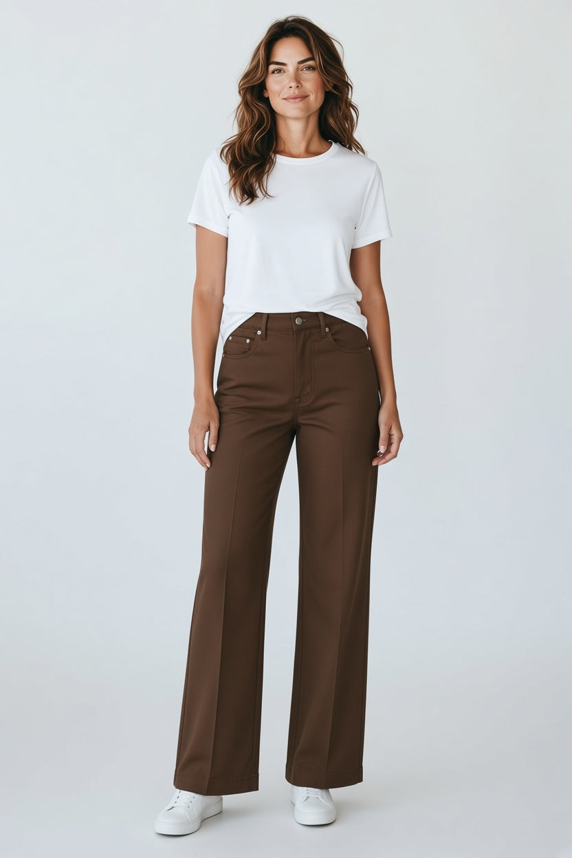 A person wearing a white crew-neck t-shirt, brown high-rise wide-leg MERSEA - STEVIE PANTS IN ESPRESSO, and white sneakers.