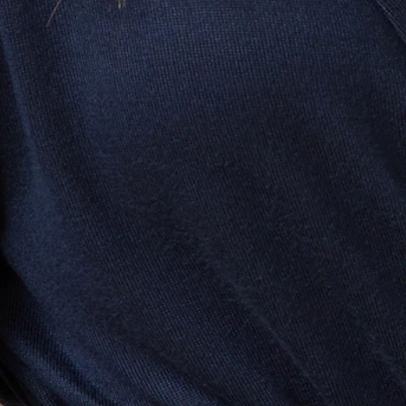 A woman wears a navy blue SOFTIES - DREAM JERSEY COWL NECK LOUNGE SET consisting of a long-sleeved top and wide-leg trousers.