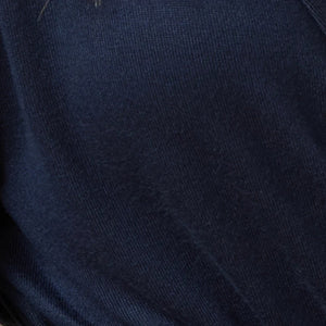 A woman wears a navy blue SOFTIES - DREAM JERSEY COWL NECK LOUNGE SET consisting of a long-sleeved top and wide-leg trousers.