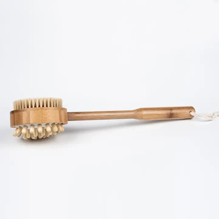 The BAUDELAIRE - BAMBOO 14&quot; MASSAGE BRUSH by BAUDELAIRE is displayed against a plain white background. It features a long handle and soft bristles, with a white rope loop attached to the end of the handle for convenient hanging. The round brush head is specifically designed for natural exfoliation and promoting healthy circulation during body scrubbing.
