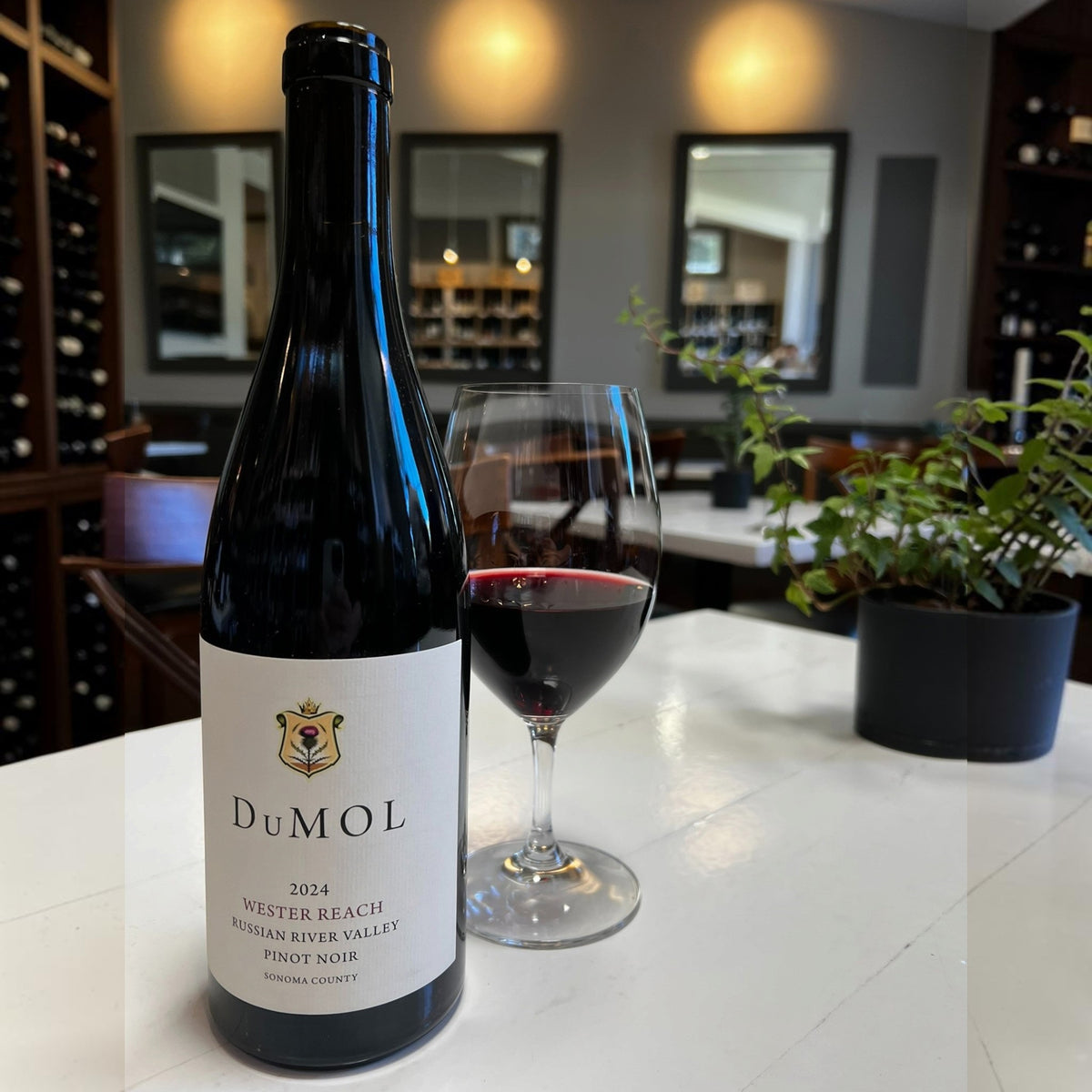 A bottle of DUMOL WESTER REACH PINOT 2024 with a cream-colored label featuring a thistle crest and the DuMOL brand name, including details for the Russian River Valley and Sonoma County.