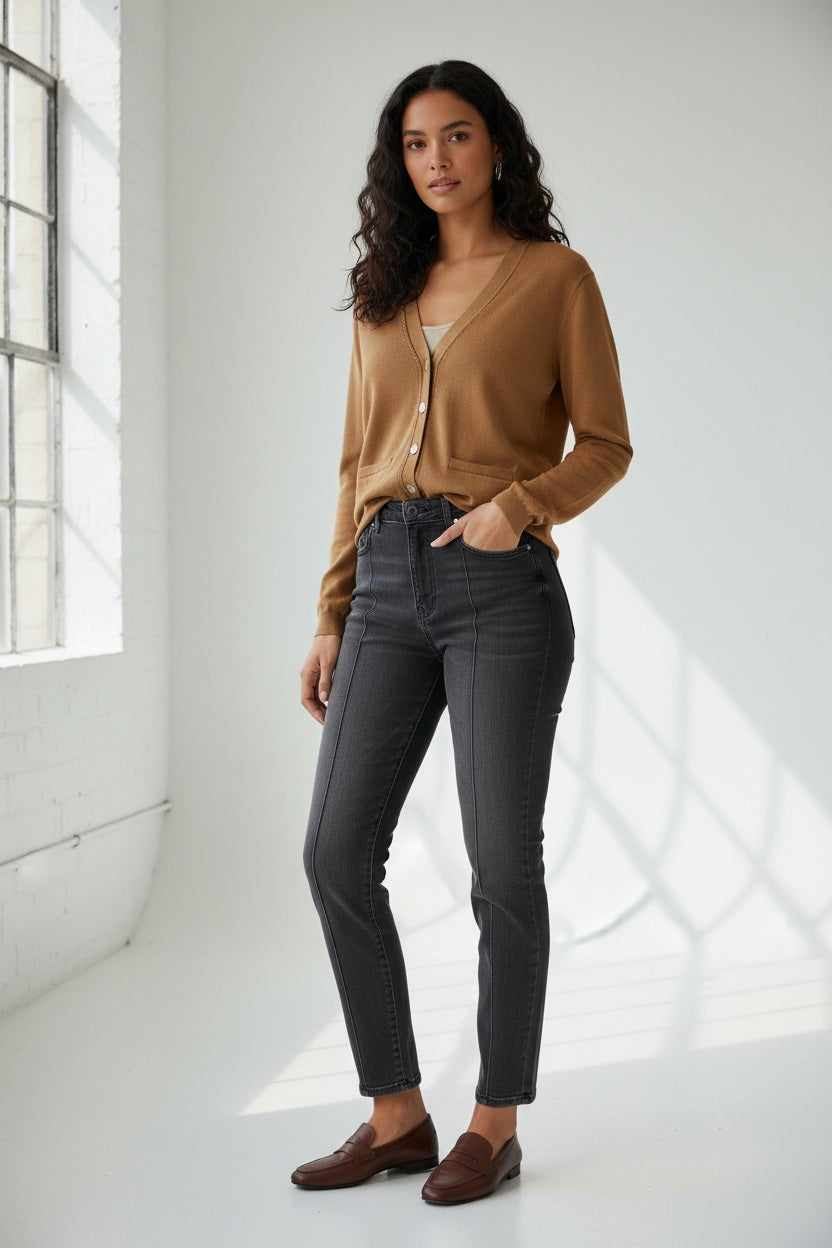 A woman with straight brown hair wears the HINSON WU CASSIE Long Sleeve Cotton Silk Cardigan in camel, styled with black pants. She poses confidently, one hand to her chin, against a neutral backdrop.