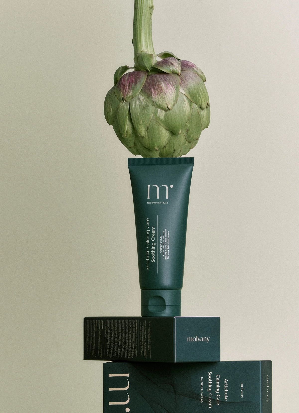 A green tube of &quot;MOLVANY - Artichoke Calming Care Soothing Cream,&quot; enriched with calming elements, sits next to its matching box. Both feature minimalistic white text with the brand name &quot;HONG CHEON USA, INC&quot; at the top. It&#39;s 100 ml / 3.4 fl. oz., promising enhanced skin moisture and tranquility.