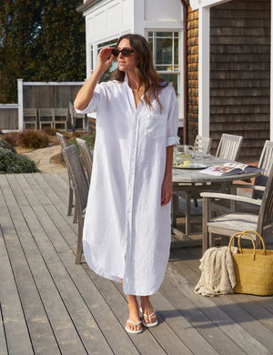 Close-up of a person wearing the FRANK & EILEEN Megan One Size Maxi Shirtdress in washed linen white with a front pocket and rolled-up sleeve. A gold necklace with a small pendant is visible on their neck.