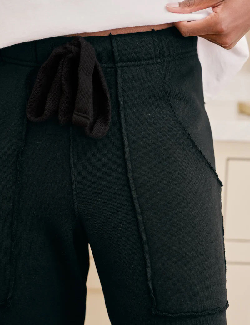 The FRANK &amp; EILEEN Penny Patch Pocket Sweatpant in black features a cropped wide-leg style, elastic drawstring waistband, and large front patch pockets, crafted from cozy triple fleece and shown flat on a white background.