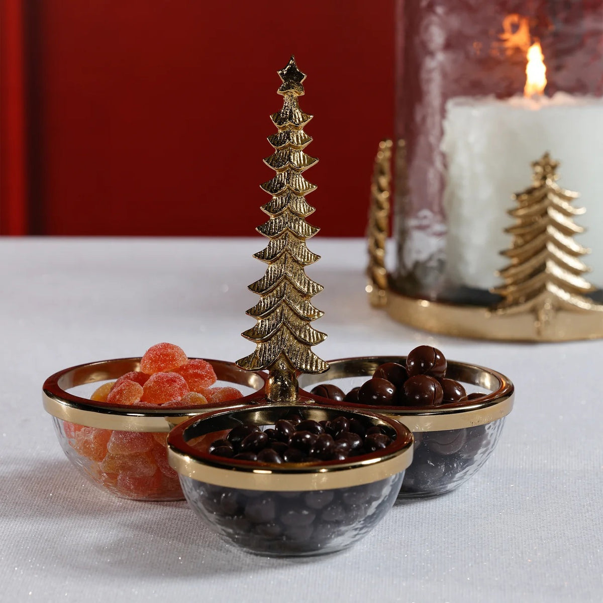 ZODAX GLASS AND ALLOY TRIO CONDIMENT SET IN GOLD featuring three glass condiment bowls with gold rims joined by a central aluminum Christmas tree stand.