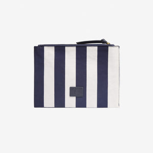 INOUI EDITIONS - POSEIDON POUCH IN NAVY by INOUI features vertical navy and white stripes, a navy zipper, and a small square patch on the front. Inspired by traditional weaving for timeless style, shown against a plain white background.