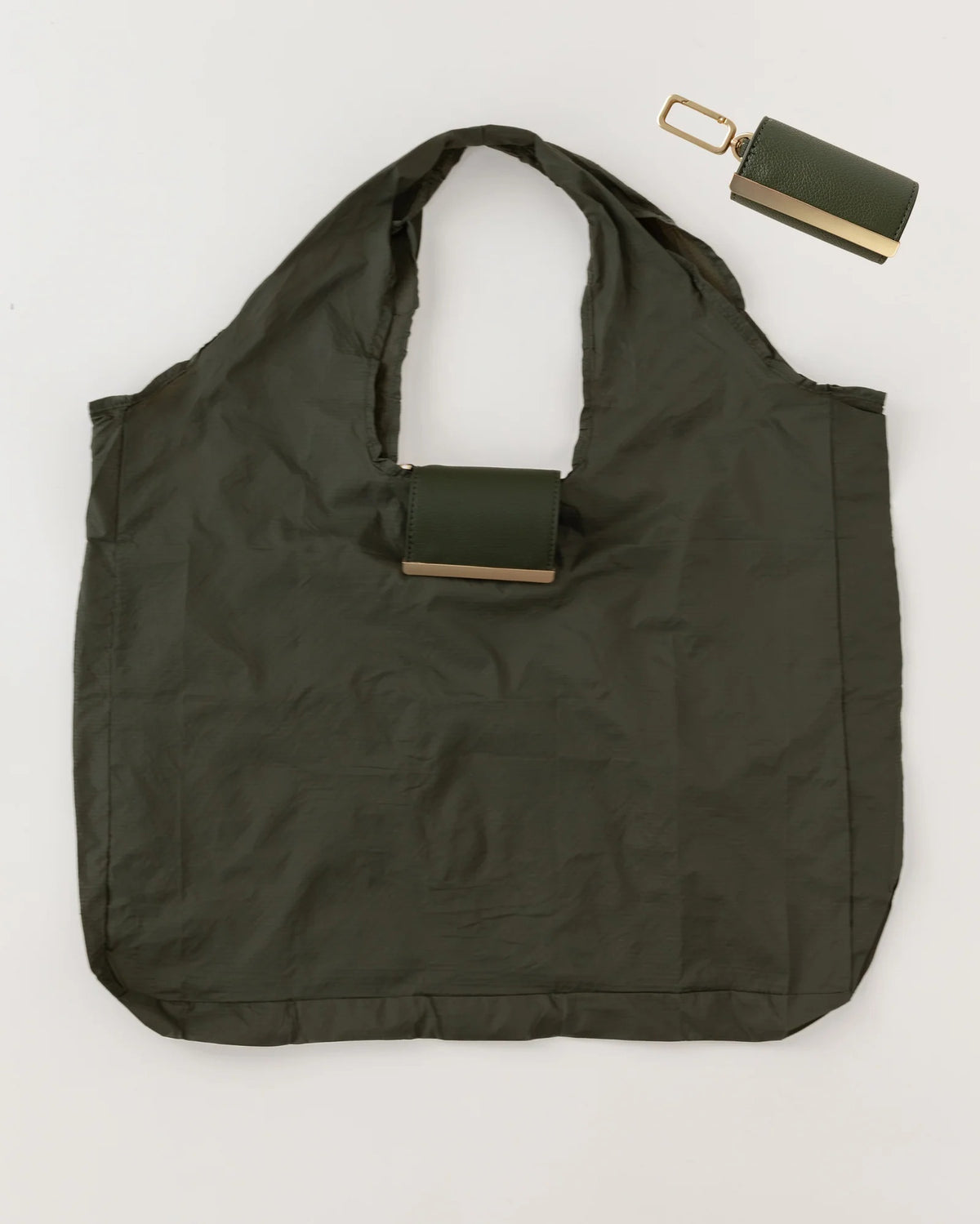 The KEOTE - KEYCHAIN TOTE IN OLIVE by KEOTE is shown flat with a matching foldable case attached to the handle, and a separate rectangular pouch placed at the top right corner.
