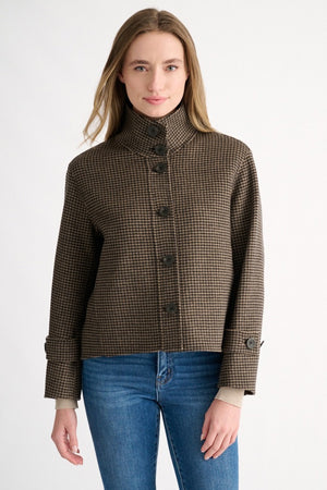 A woman with straight, light brown hair is seen from behind wearing the KINROSS KINROSS CASHMERE HOUNDSTOOTH BUTTON MOCK COAT and blue jeans against a plain white background.