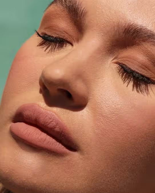 A container of JASON WU BEAUTY - READY SET MATTE 1 - TRANSLUCENT BANANA setting powder sits on a light brown textured surface. The cylindrical container has a black lid with the brand name in white capital letters and product details in both English and French, ensuring a flawless matte finish for any makeup look.