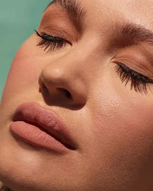 A container of JASON WU BEAUTY - READY SET MATTE 1 - TRANSLUCENT BANANA setting powder sits on a light brown textured surface. The cylindrical container has a black lid with the brand name in white capital letters and product details in both English and French, ensuring a flawless matte finish for any makeup look.