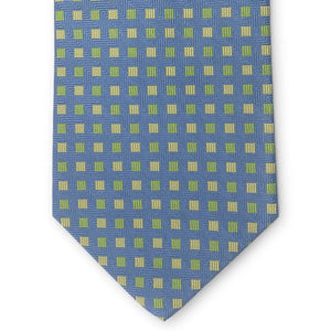 Introducing the PETER-BLAIR - BESPOKE SMALL SQUARES SILK TIE IN BLUE by BIRD DOG BAY: a rolled navy blue woven silk tie, artfully detailed with a pattern of small yellow and green squares on a white background.