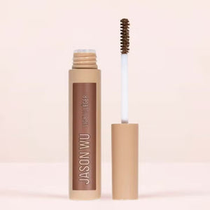 A cylindrical makeup product labeled "FREE DA BROW LIGHT 2" by JASON WU BEAUTY in white text against a beige background. The container features a matte finish and a beige cap, designed to help you define your brows effortlessly. Set against a neutral, light-colored background, the image captures its sleek elegance.