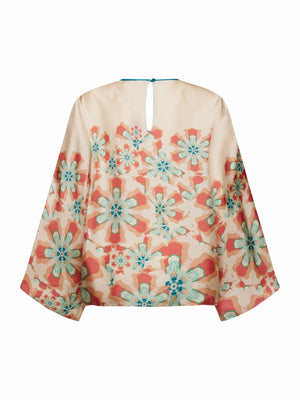 The FRANCO FERRARI - WIDE SLEEVE CORAL BLOUSE features a flowy, lightweight silk design with a floral print in teal, orange, and beige. Perfect for vacation dressing, it has a slightly sheer fabric with a round neckline and back button closure.