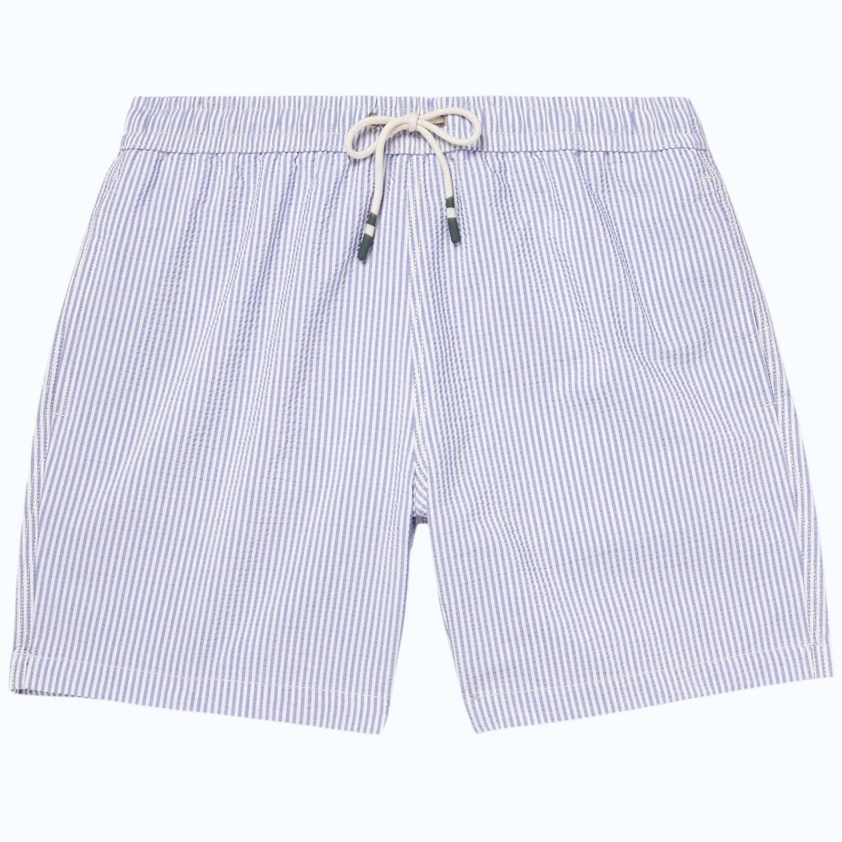 A person wears HARTFORD - SEERSUCKER SWIM TRUNKS IN INDIGO with a drawstring waist, side pockets, and a quick-drying seersucker fabric. The mid-thigh trunks are shown against a plain background, displaying only the torso and legs.