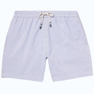 A person wears HARTFORD - SEERSUCKER SWIM TRUNKS IN INDIGO with a drawstring waist, side pockets, and a quick-drying seersucker fabric. The mid-thigh trunks are shown against a plain background, displaying only the torso and legs.