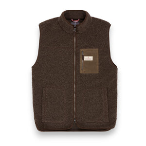 The AMUNDSEN SPORTS Heroes Fleece Vest in Cowboy features a brown sherpa wool texture, front zipper, high collar, two large side pockets, and a chest pocket with a tan patch for warmth and style.