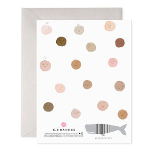 The E. FRANCES PAPER - WELCOME BABY GREETING CARD by E. FRANCES PAPER is a handcrafted watercolor card with "welcome baby!" in light blue, featuring smiling circular faces in diverse skin tones with little hair tufts, paired with a gray envelope, proudly made in the USA.