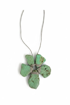 The ANN LIGHTFOOT - ROUGH CUT CHRYSOPRASE FLOWER NECKLACE by ANN LIGHTFOOT features four irregular green chrysoprase stones arranged in a flower-like shape, secured with wrapped cord and suspended from a delicate silver chain, shown against a white background.