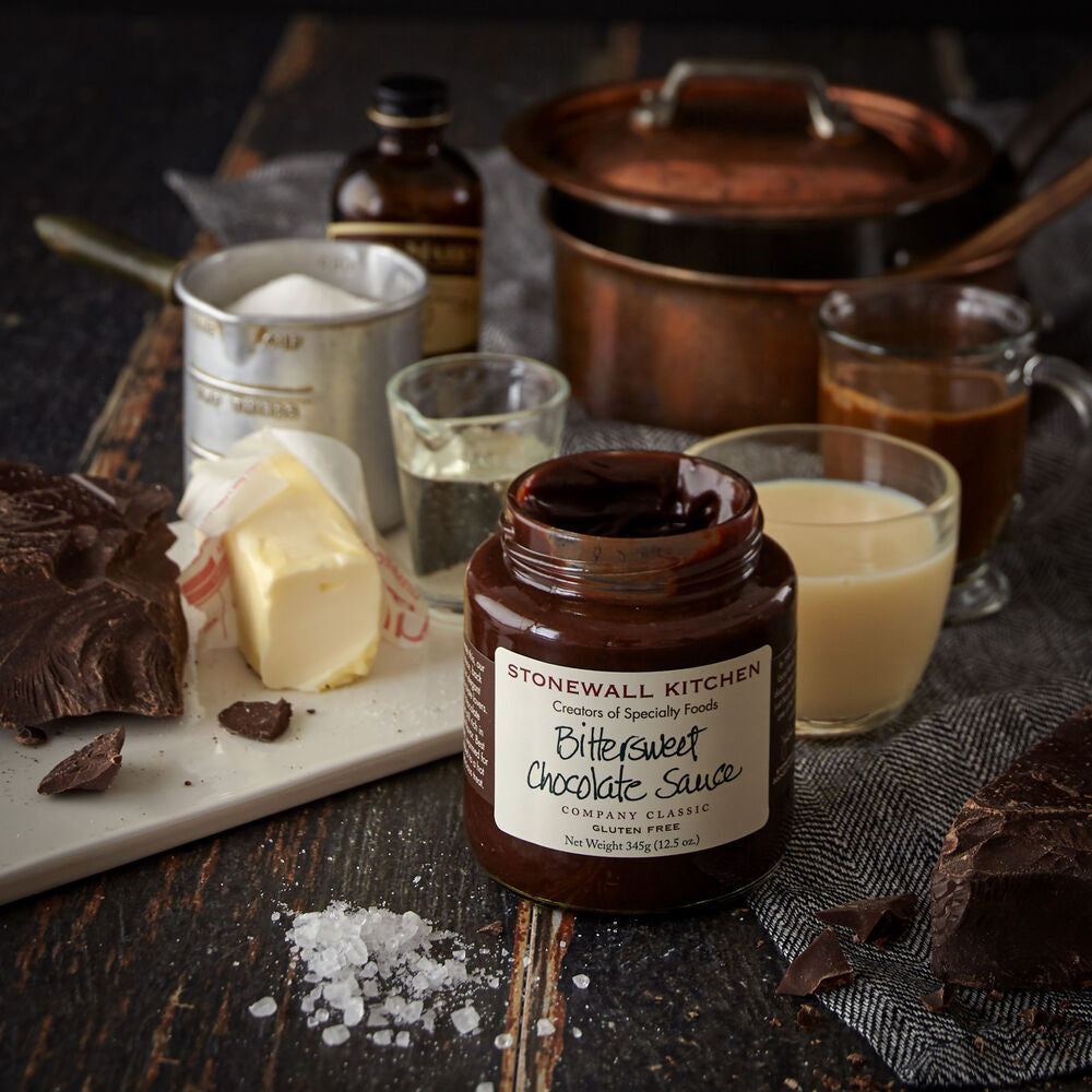 A jar of STONEWALL KITCHEN- BITTERSWEET CHOCOLATE SAUCE featuring a dark green lid promises a rich chocolate flavor. The label clearly states that it is gluten-free and weighs 354g (12.5 oz.). This hot fudge sauce is described as a classic from the brand, making it ideal for any dessert indulgence.