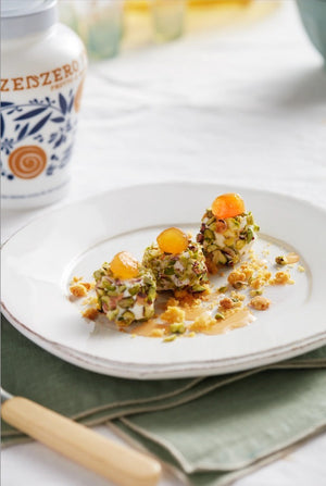 A vibrant jar of FABBRI - CANDIED GINGER IN SYRUP by Gourmet Food Solutions, featuring a decorative blue and white lid and an intricate orange and blue design on the glass. The front label prominently displays "Gluten Free." The jar is set against a white background, capturing the essence of candied ginger.