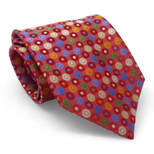 The BIRD DOG BAY PETER-BLAIR Bespoke Circle Field Woven Silk Tie in red showcases colorful polka dots and is handmade in New York. Neatly rolled, it is displayed on a white surface.