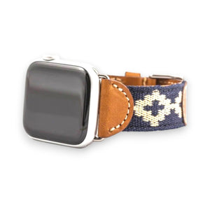 The LA MATERA - CORBINA Apple Watch Band in silver pairs artisan brown leather with a black fabric section, beige geometric pattern, and red stitching.