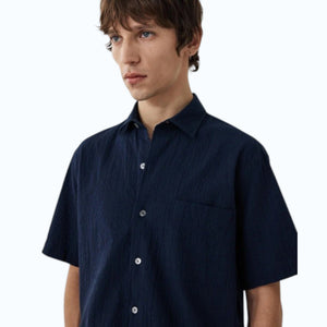 A young man with short brown hair wears the HARTFORD - PEDRO SHIRT IN NAVY and light blue jeans, standing against a plain white background.