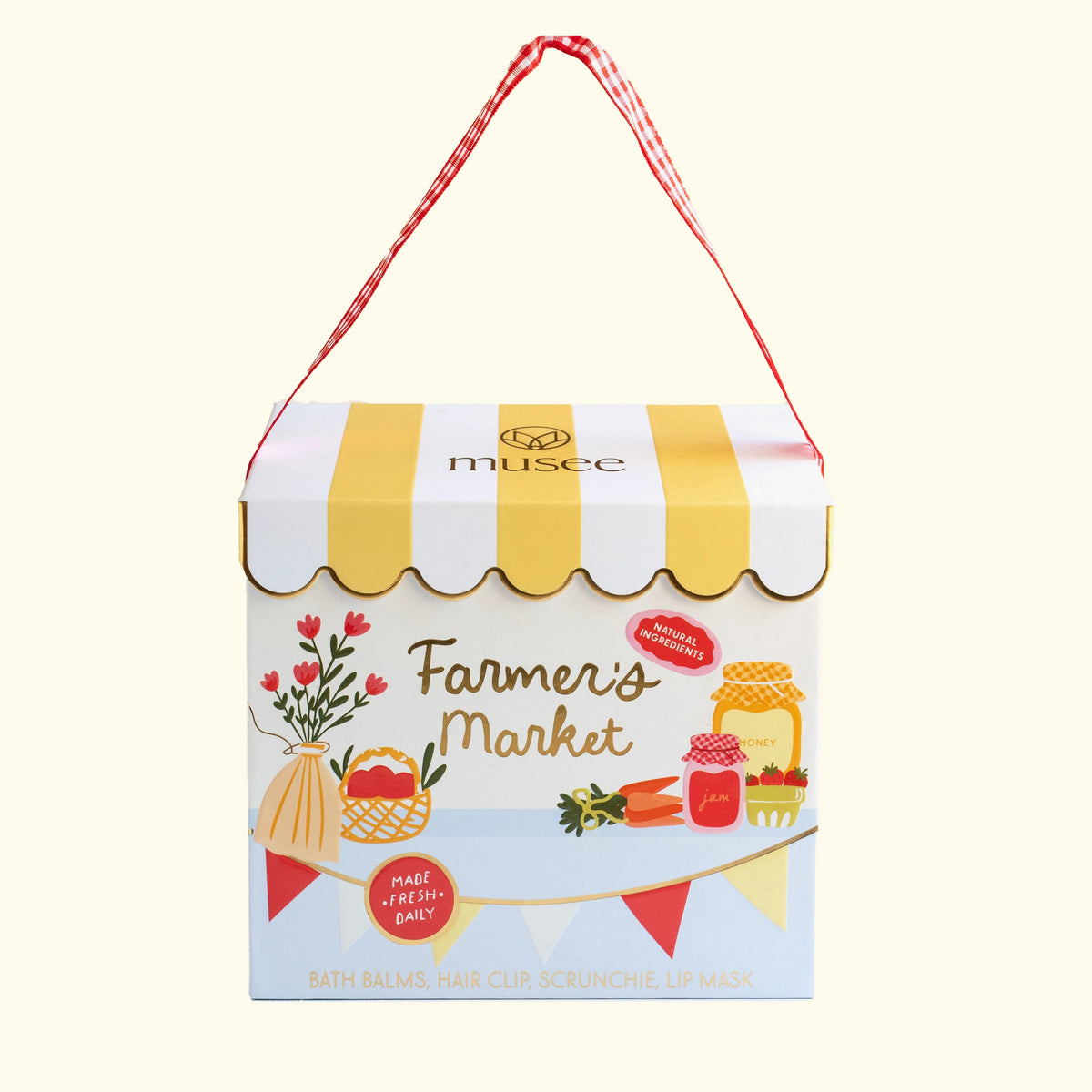 MUSEE - FARMERS’ MARKET GIFT SET by MUSEE features two soothing bath balms, a pink hair clip, a hydrating lip mask, and a red gingham scrunchie—all beautifully packaged in a decorative box adorned with checkered trim and delightful fruit illustrations.