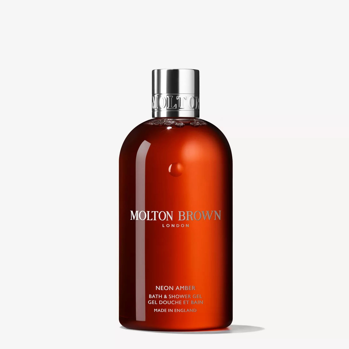 A 300ml bottle of MOLTON BROWN - NEON AMBER BATH AND SHOWER GEL with a silver cap, translucent amber-orange body, and white text is displayed on a plain white background.