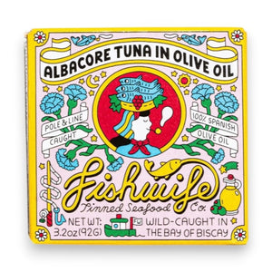 A vibrant tin of FISHWIFE Albacore Tuna in Olive Oil features a vintage-inspired design with a woman, flowers, lemons, and banners highlighting the product’s wild-caught and MSC-certified albacore tuna packed in Spanish olive oil.