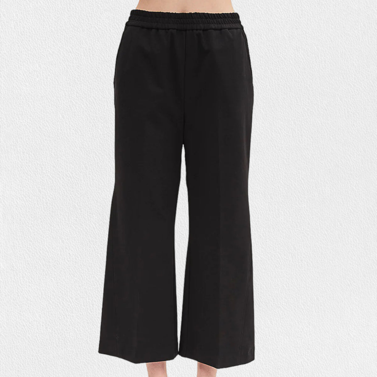 A person is wearing black, pull-on straight-leg cropped pants from MEIMEIJ with an elastic waistband. The bottom part of their legs and feet are visible, highlighting the sleek seam detail, but the top part of the body is not shown. The background is plain white.