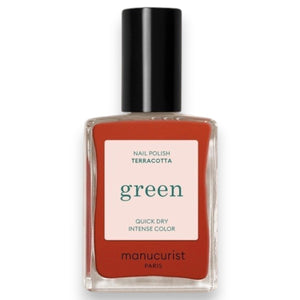 A hand with a glossy coat of MANUCURIST - GREEN™ NAIL POLISH IN TERRACOTTA by MANUCURIST INC touches an ear adorned with a chunky, abstract silver earring against brown skin.