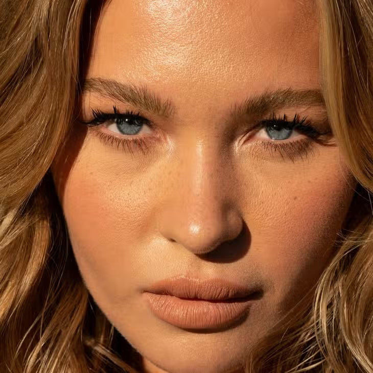 A cylindrical makeup product labeled &quot;FREE DA BROW LIGHT 2&quot; by JASON WU BEAUTY in white text against a beige background. The container features a matte finish and a beige cap, designed to help you define your brows effortlessly. Set against a neutral, light-colored background, the image captures its sleek elegance.